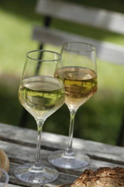 İki kadeh beyaz şarap ve bir şişe beyaz şarap.