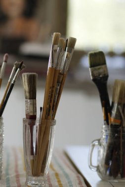 Kapalı alandaki masada farklı boya ve fırçalar var. Yakın plan. Metin için boşluk