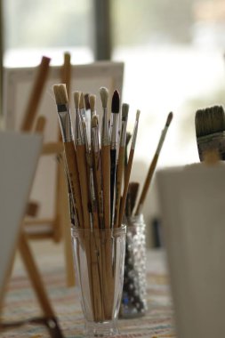 Arkadaki masada fırçalar ve boya fırçaları sanatçıyla birlikte.