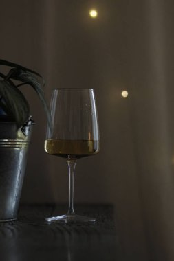 Karanlık bir duvarın arka planında bir şişe şarap bardağı ve akşamları boş bir pencere..