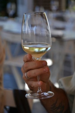 Yakından. Elinde beyaz şarap olan bir adamın fotoğrafı..