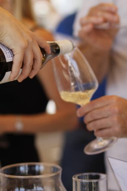 Bardağa beyaz şarap dolduran kadına yakın dur.