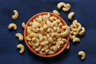 Mavi arka planda bir kasede kavrulmuş kaju fıstığı.