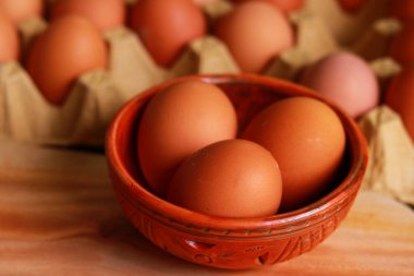 Fresh eggs in a bowl on a wooden table. Selective focus. clipart