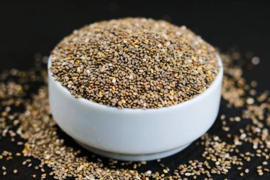 Siyah arka planda bir kasede Chia tohumları. Seçici odak.