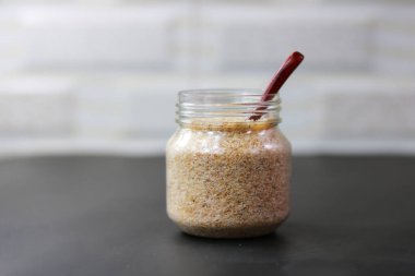 Cam bir kavanozda, arka planda tahta bir kaşıkla psilyum kabuğu (Isabgol).