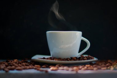 Siyah arka planda kahve fincanı ve kahve çekirdekleri.