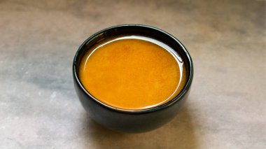 Gri arka planda siyah bir seramik kasede saf ghee..