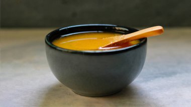 Siyah arka planı olan siyah bir kâse üzerinde tahta bir kaşıkta Ghee.