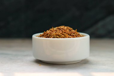 Beyaz bir porselen kasede kurutulmuş kimyon tohumları.