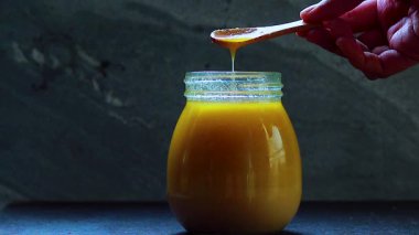 Tahta kaşıktan cam kavanoza damlayan Ghee