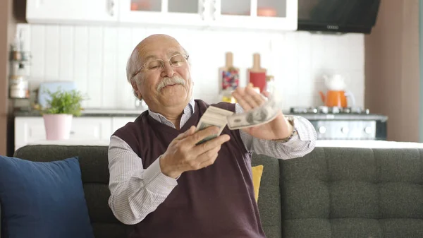 老人坐在沙发上 把钞票抛向空中 把它们扔到一边 一个快乐人的画像 因为他从赌博中赚了很多钱 — 图库照片