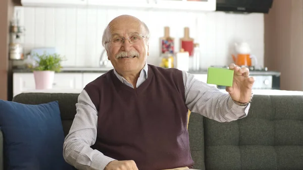 Starý Muž Ukazuje Zelenou Skříňku Imaginární Produkt Pohovce Usmívá Tvůrčí — Stock fotografie