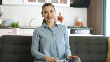 Gülümseyen güzel bir genç kadının portresi. Evindeki mutlu ve huzurlu kadın kameraya gülümsüyor..