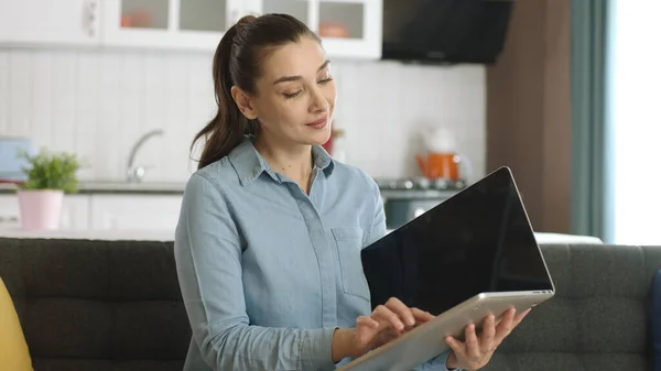 Young woman holding her laptop like a book. Young woman switching pages as if reading a book on her laptop. The woman is surprised by what she sees on her laptop. Future technology.