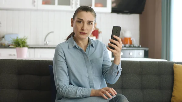 Ελκυστική Νεαρή Γυναίκα Που Χρησιμοποιεί Smartphone Ενώ Κάθεται Στον Καναπέ — Φωτογραφία Αρχείου