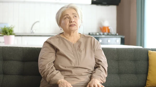 一个安静的老妇人躺在她宁静的家里的沙发上 寂寞的白发苍苍的女人对着摄像机右边空旷的广告空间说话 有创意的人可以把他们想要的任何东西放在 — 图库照片