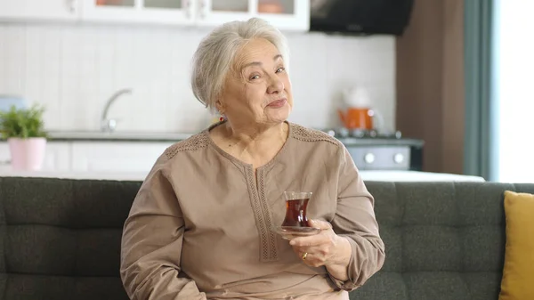 Mutlu Yaşlı Kadın Çay Içerken Televizyonda Ilginç Bir Film Izliyor — Stok fotoğraf