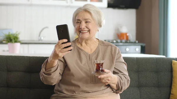 Ευτυχισμένη Γιαγιά Που Κρατάει Κινητό Βιντεοκλήση Αγαπημένους Ενώ Πίνει Τσάι — Φωτογραφία Αρχείου