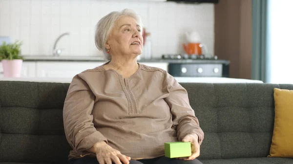 Stará Žena Drží Něco Zeleného Svém Křesle Ukazuje Produkt Usmívá — Stock fotografie