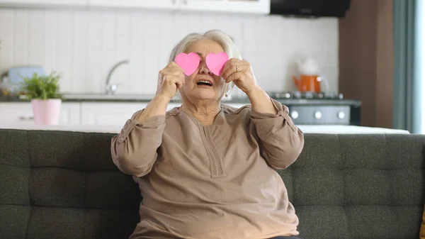快乐的老妇人 手里拿着两颗粉色的小纸心 跳舞着 亲吻着心爱的人 爱情在眼睛 情人节 母亲节 爱情在眼睛 浪漫的概念 — 图库照片