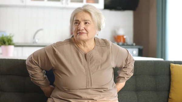 快乐的老妇人在家里或养老院 老年人保健服务 老太婆坐在客厅沙发上 看着屏幕左边空旷的广告空间的画像 — 图库照片