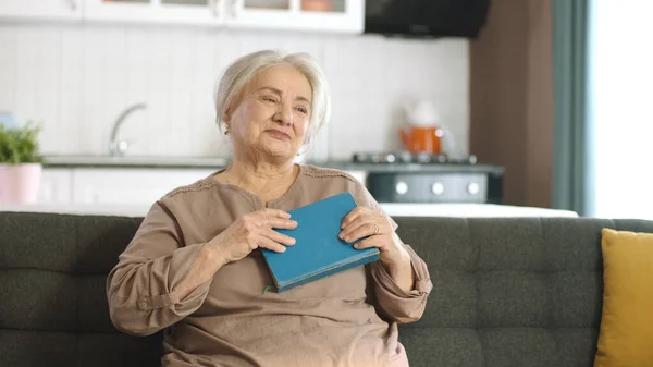 白发苍苍的老妇人胸前抱着一本旧书 — 图库照片