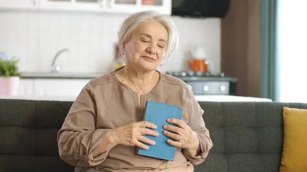 白发苍苍的老妇人胸前抱着一本旧书 — 图库照片