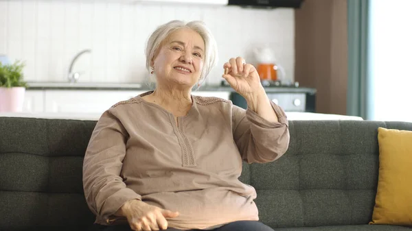 Starší Bělovlasá Žena Ukazuje Pilulku Pohovce Obývacím Pokoji Poukazuje Lék — Stock fotografie