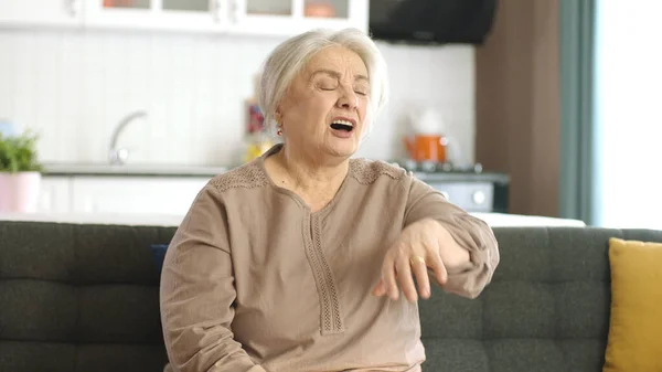The first symptoms of cold and flu virus appeared in the old woman. Woman suffering from lack of oxygen and shortness of breath while sitting at home. Allergy, sneezing attacks.