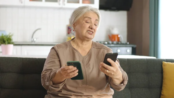 Ηλικιωμένη Γυναίκα Κοιτάζει Τους Λογαριασμούς Κοινωνικής Δικτύωσης Δύο Smartphones Διαβάζει — Φωτογραφία Αρχείου
