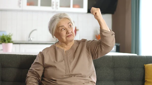 Starsza Kobieta Podnosi Ręce Pokazuje Bicepsy Przed Kamerą Domu Feminizm — Zdjęcie stockowe