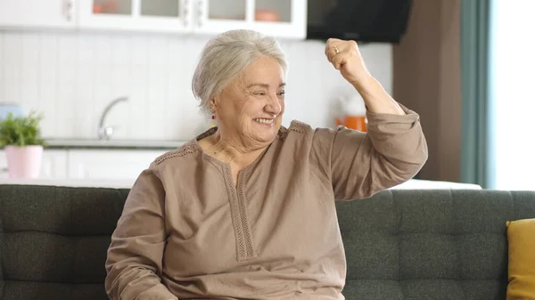 一位老年妇女举起胳膊 在家里的摄像机前展示她的二头肌 女权运动和妇女权力 那位老妇人说她仍然强壮 健康生活 妇女健康概念 — 图库照片