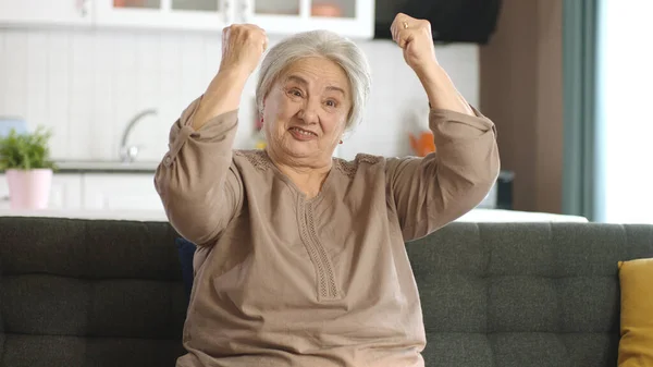 一位老年妇女举起胳膊 在家里的摄像机前展示她的二头肌 女权运动和妇女权力 那位老妇人说她仍然强壮 健康生活 妇女健康概念 — 图库照片
