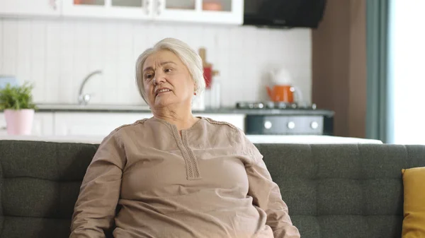 有思想的老妇人在家里或养老院里 老年人保健服务 老妇人坐在客厅沙发上看着左边空白的广告空间的画像 — 图库照片