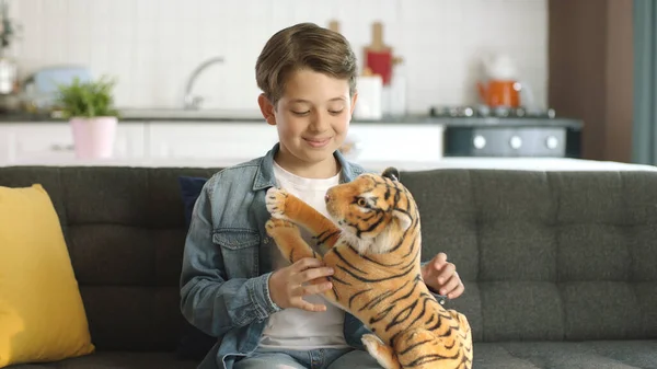 Stock image Home alone, little boy without friends plays with a toy tiger.Brown toy tiger in child's hand. Child playing with a toy tiger in the living room.