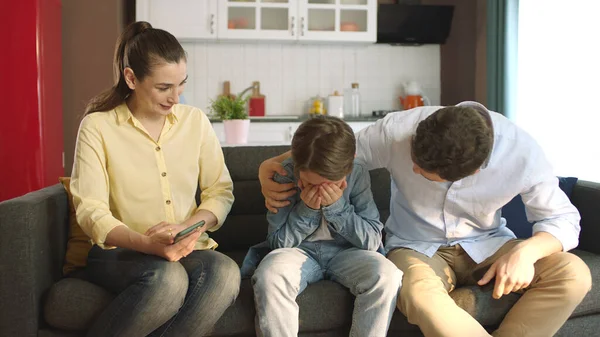 Young couple comforting their sad little son in the living room of their home.Portrait of parents caring for their children. The family hugs their children who are having problems at school.
