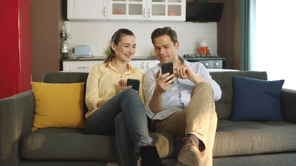 Happy Couple Talking Laughing Sofa Looking Smartphone Using Apps Young — Stock Photo, Image