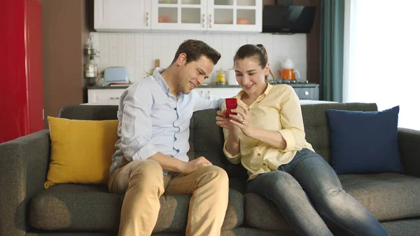 A young man gives his girlfriend a beautiful ring as a Valentine\'s Day gift. Young man showing engagement ring to his girlfriend at home. Marriage proposal.