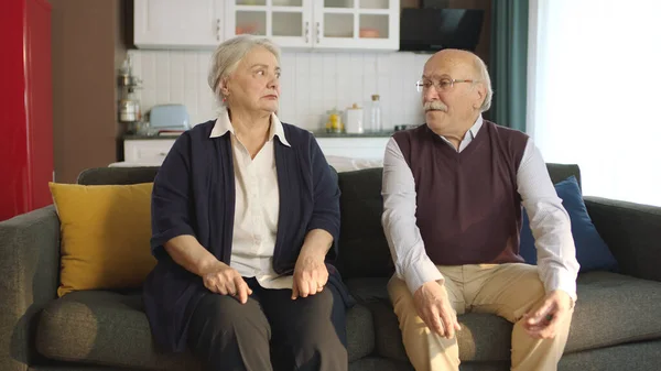 Thoughtful elderly couple sitting in their armchair at home and not talking to each other. Image of an elderly couple in troubled marriages. Problems experienced by married couples.
