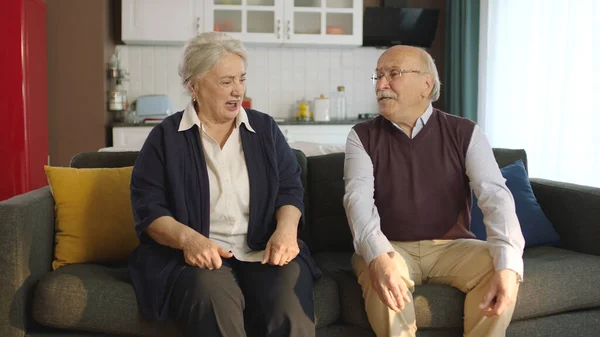 Thoughtful elderly couple sitting in their armchair at home and not talking to each other. Image of an elderly couple in troubled marriages. Problems experienced by married couples.
