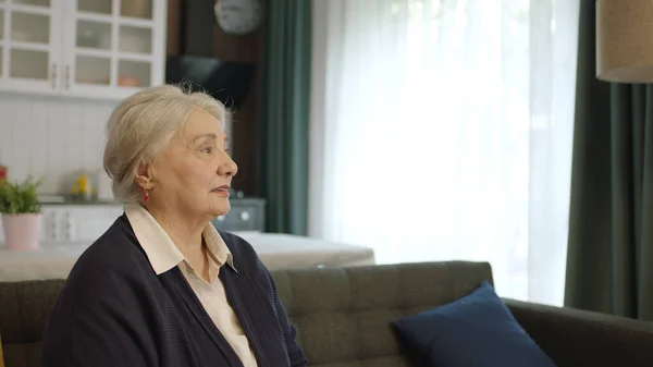 Sad, thoughtful and unhappy old woman alone at home. The worried old woman was lost in thought. Loneliness grief concept. Woman feeling anxious alone at home.