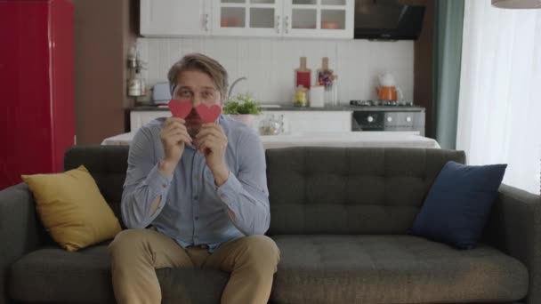 Gözlerinde Iki Kağıt Kalple Oynayan Mutlu Adamın Videosu Evinin Kanepesinde — Stok video