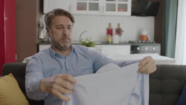 Joven Buscando Manchas Camisa Recién Lavada Hombre Está Olfateando Camisa — Vídeo de stock