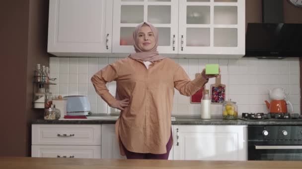 Женщина Хиджабе Держит Зеленое Кухне Показывает Продукт Улыбается Представляет Веселый — стоковое видео
