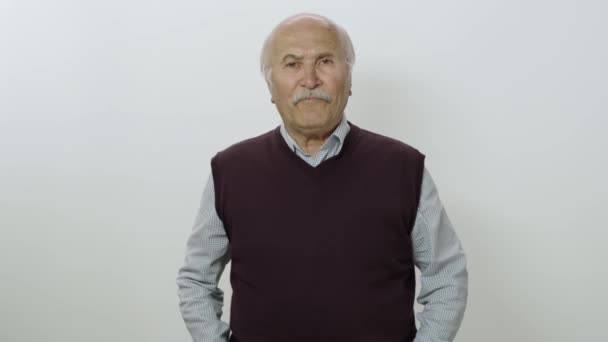 一个漫不经心的中立老人的画像 有爱心的老人看着相机 基于白色背景孤立的老人的工作室肖像 — 图库视频影像