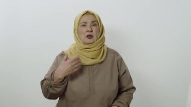 Seyretmek istemiyorum! Güzel bir sarıklı yaşlı kadın gözlerini kapatıp jest yapıyor. Utanç verici içeriğe bakmak için kafası karışık ve utangaç. Beyaz üzerine kapalı stüdyo çekimi..