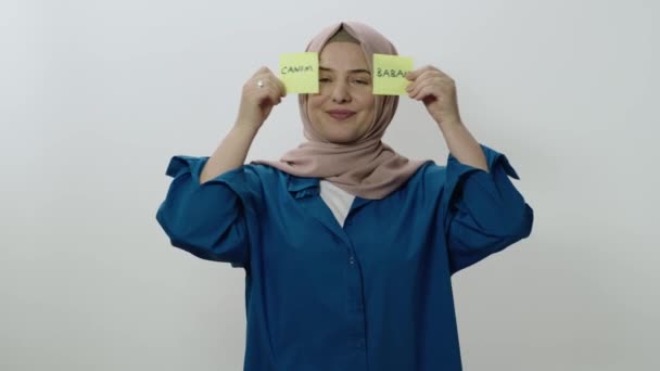 一个年轻的女人站在一个白色的背景前 一个快乐的女人拿着纸条的视频 上面用土耳其语写着 亲爱的爸爸 情人节 母亲节 父亲节的概念 — 图库视频影像