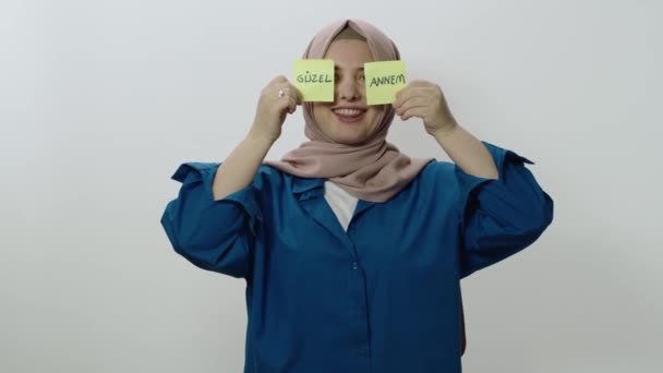 一个年轻的女人站在一个白色的背景前 一个快乐的女人拿着纸条的视频 上面用土耳其语写着 亲爱的爸爸 情人节 母亲节 父亲节的概念 — 图库视频影像