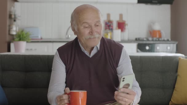 Old Man Spends Time His Smartphone While Drinking Coffee Home — Stock Video